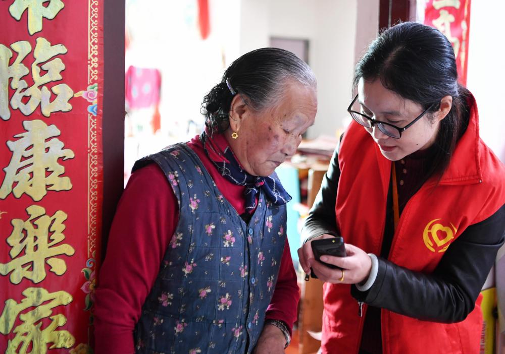 在福州市长乐区航城街道筹岐村，智慧养老平台派驻社区的助老员（右）在为老人陈凤英（左）讲解养老定制手机的用法（2021年11月26日摄）。新华社记者 魏培全 摄