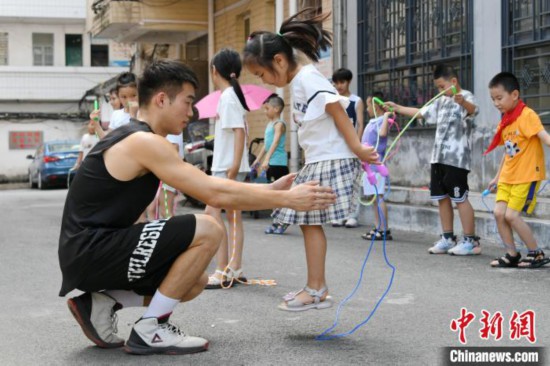 图为大学生志愿者在教孩子们学跳绳。廖光福 摄