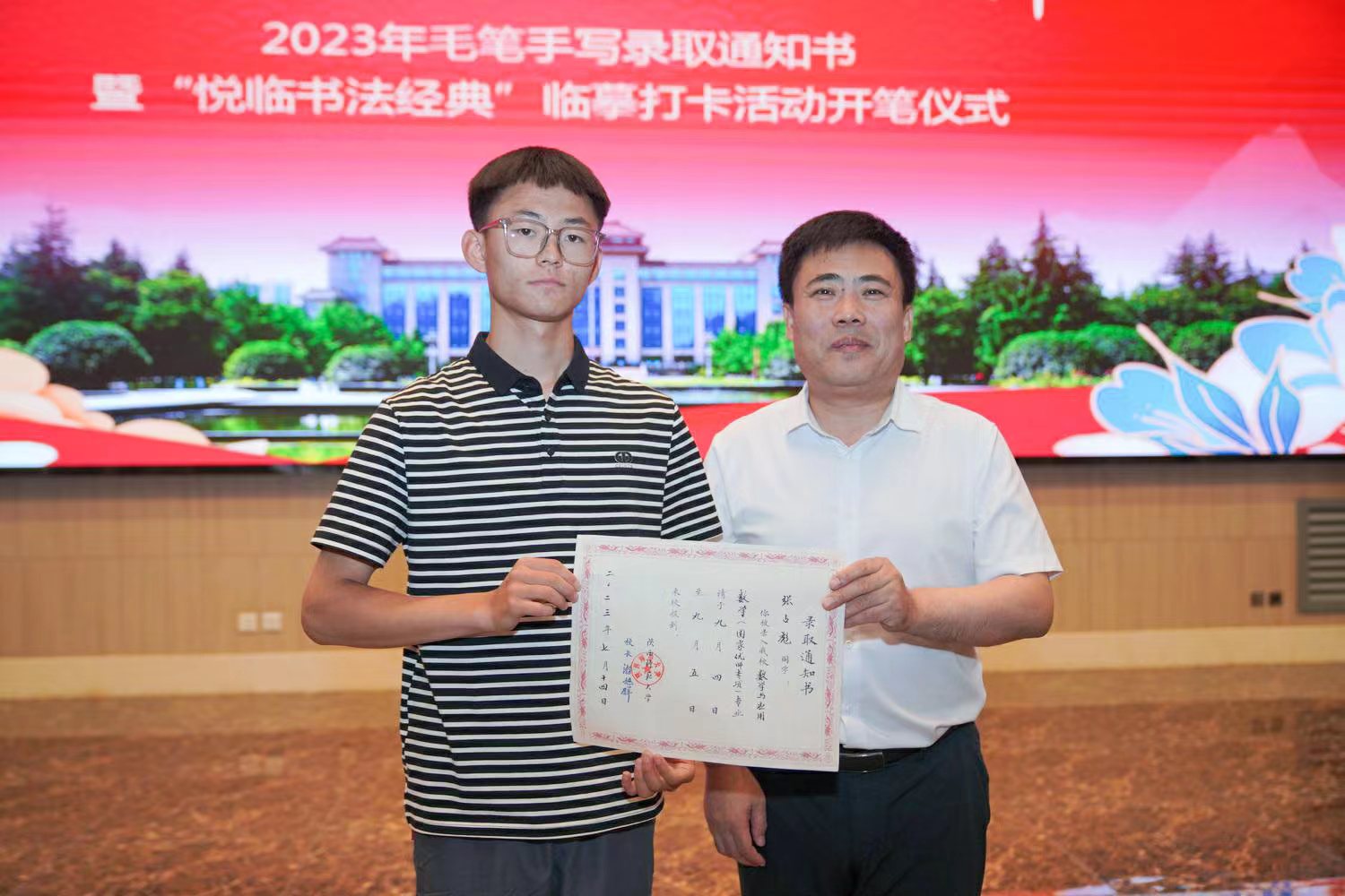 陕西师范大学党委书记李忠军为2023级新生代表张占彪同学发放录取通知书。校方供图