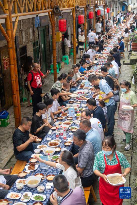 7月29日，在重庆市綦江区安稳镇，人们在“苗家伏羊节”上吃长桌宴。新华社记者 唐奕 摄