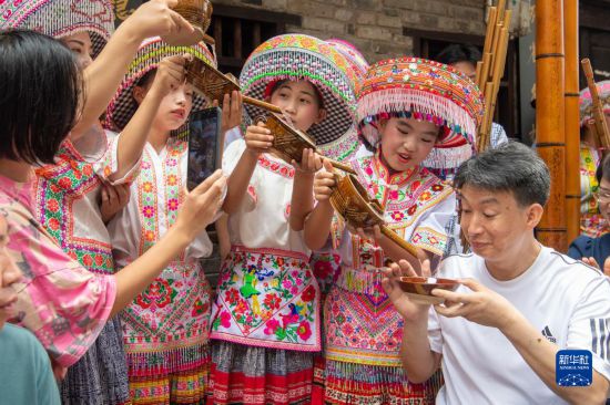 7月29日，在重庆市綦江区安稳镇，当地居民在“苗家伏羊节”上用传统习俗向游客表达祝福。新华社记者 唐奕 摄