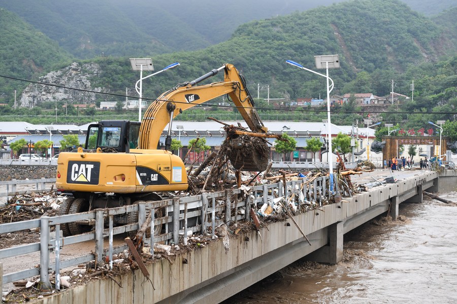 8月1日，在北京市门头沟区水峪嘴村村口，一台挖掘机在清理阻断桥梁交通的杂物。目前该条道路已经疏通完成。新华社记者 鞠焕宗 摄