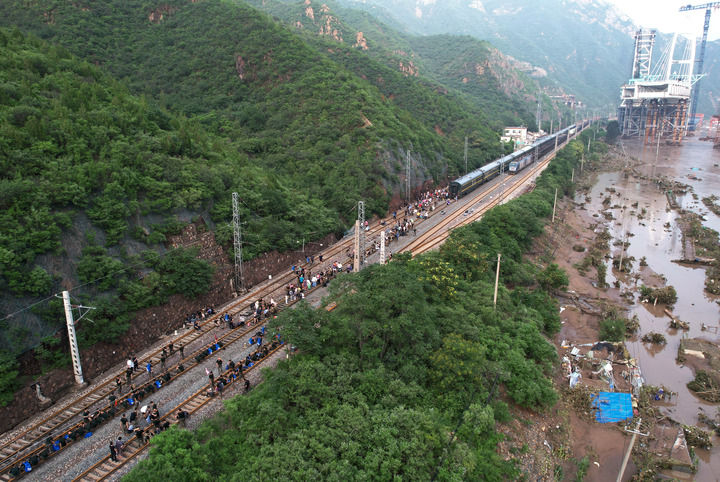 8月2日，受困列车旅客在救援人员帮助下徒步赶往转运客车（无人机照片）。新华社记者 张晨霖 摄