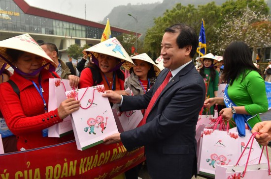 3月15日，在越南谅山省的友谊国际口岸，越南文化体育与旅游部旅游总局副局长何文超（前右二）向中国游客发放纪念品。（新华社记者胡佳丽摄）