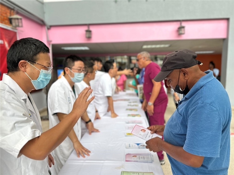 援圭医疗队队员们在启动仪式上为当地民众分发宣传手册。中国援助圭亚那医疗队供图