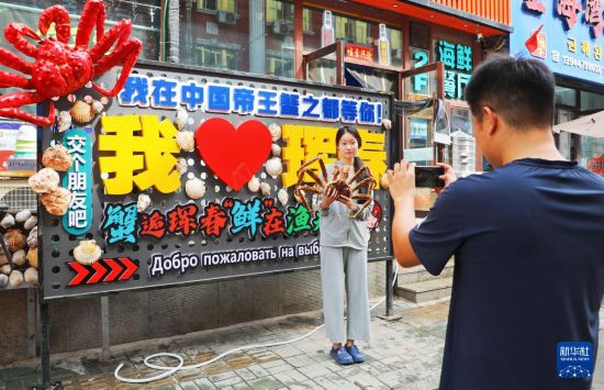 9月21日，游客在吉林省珲春市一处帝王蟹元素主题装饰前拍照留念。新华社发