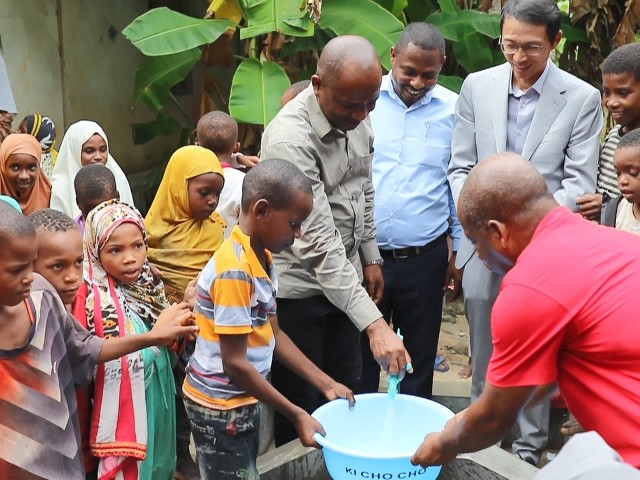 在日前举行的安全供水工程揭牌仪式上,当地小朋友在供水点接水。 施亮摄